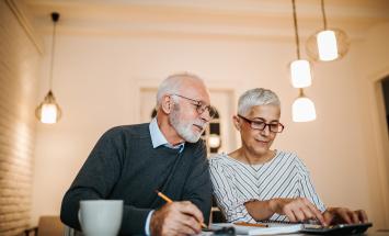 Two people with white hair doing their taxes