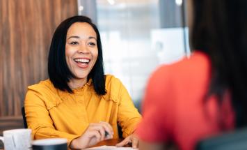 person wearing a yellow shirt and smiling at a table