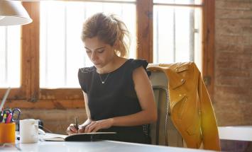 Woman sitting at desk writing in a notebook