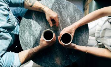 aerial photo of two people holding cups at a table