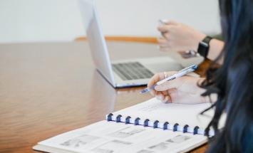 Person holding pen writing on paper