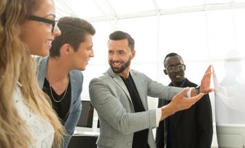 Group of people, talking and looking at a whiteboard