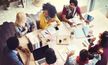 Group of people, eagle eye view, around a table working