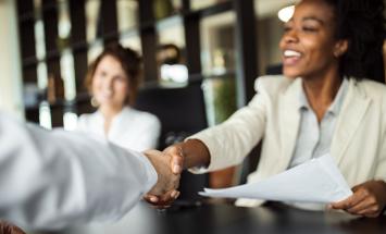 Woman shaking hands across conference room table