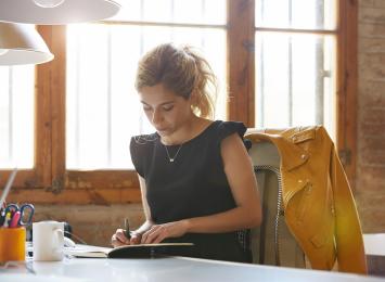 Woman sitting at desk writing in a notebook