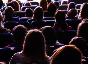 View from behind of people sitting in a darkened theater-style room