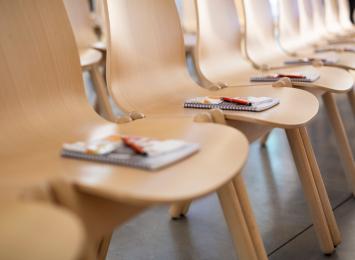row of chairs with notebooks and pens on each chair