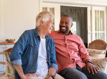 Two people on a porch looking at each other and smiling 