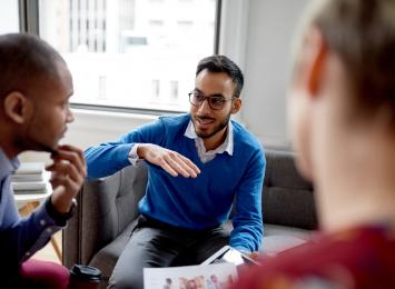 Three people talking, one is using his hands to make a point