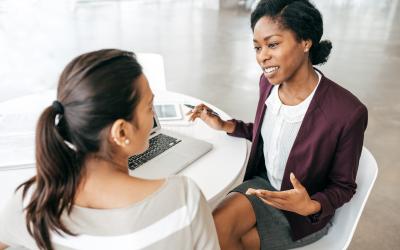 2 women talking and sharing a laptop