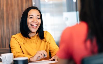 person wearing a yellow shirt and smiling at a table