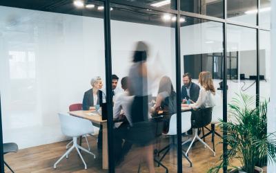 Seven people at a conference table with one person walking around the table