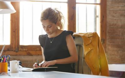 Woman sitting at desk writing in a notebook