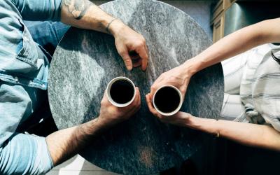 aerial photo of two people holding cups at a table