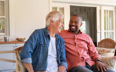 Two people on a porch looking at each other and smiling 