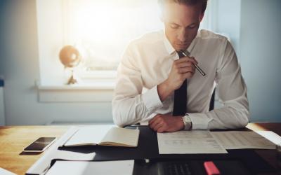 Man studying papers in front of him with sun coming in through window behind him