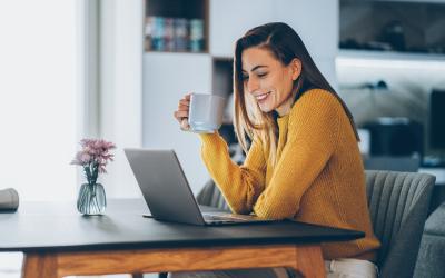 person holding a cup of coffee at the computer