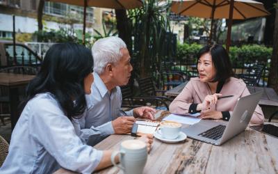 three people at an outdoor table working around a laptop