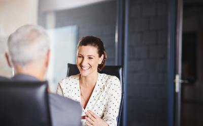 Person at desk talking to a white haired person