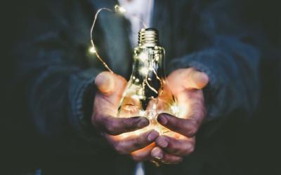 man holding light bulb with string lights